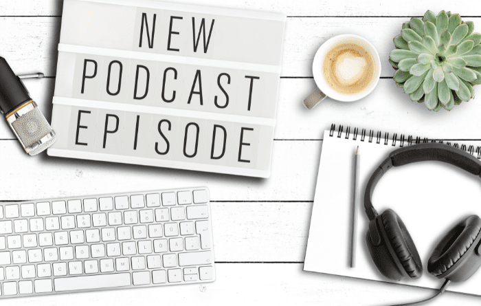Business items on desk with new podcast episode sign
