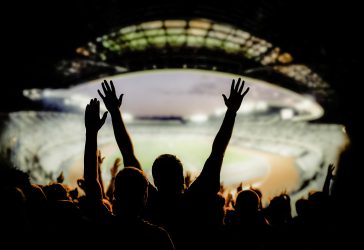 Man holding his hands high in the air in a sports stadium