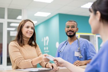 Young cheerful patient giving credit card to receptionist in clinics to pay for medical service after consultation and treatment