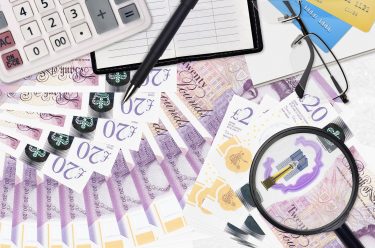 20 British pounds bills and calculator with glasses and pen. Tax payment season concept or investment solutions. Searching a job with high salary earnings