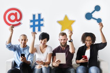 three women and men holding up social media symbols