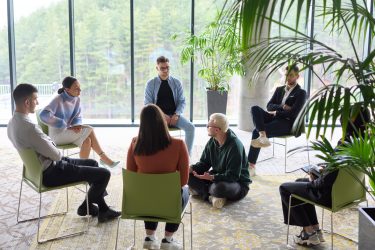 Corporate business team meeting with a manager or coach. Group of happy diverse, multiracial people sitting in a circle .