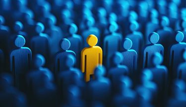A blue crowd of people with one yellow person standing out, representing the concept of standing apart from others. The background is dark and blurred to emphasize the figure in color. --ar 26:15 --v 6.1 Job ID: 9b48891d-ede9-4606-9de7-a97ca3610402